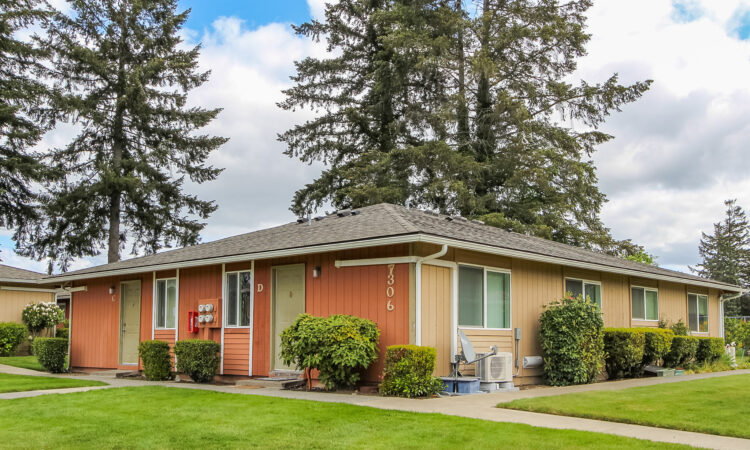 A multicolor 4-plex surrounded by green lawns and shrubs.