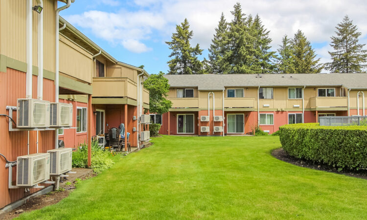 A two-story apartment complex with a green courtyard.