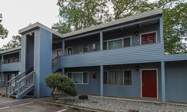 A blue two-story walkup building with red doors.